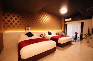 Ein Hotelzimmer mit zwei Betten, einem kleinen Tisch mit Blumenvase und einer Topfpflanze.