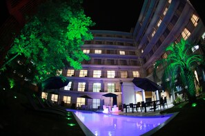 Ein Hotel mit Schwimmbad, Außenbereich und einem mehrstöckigen Gebäude mit beleuchteten Fenstern.