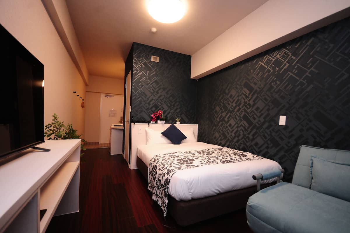 Una habitación de hotel con cama, escritorio, silla y televisor.