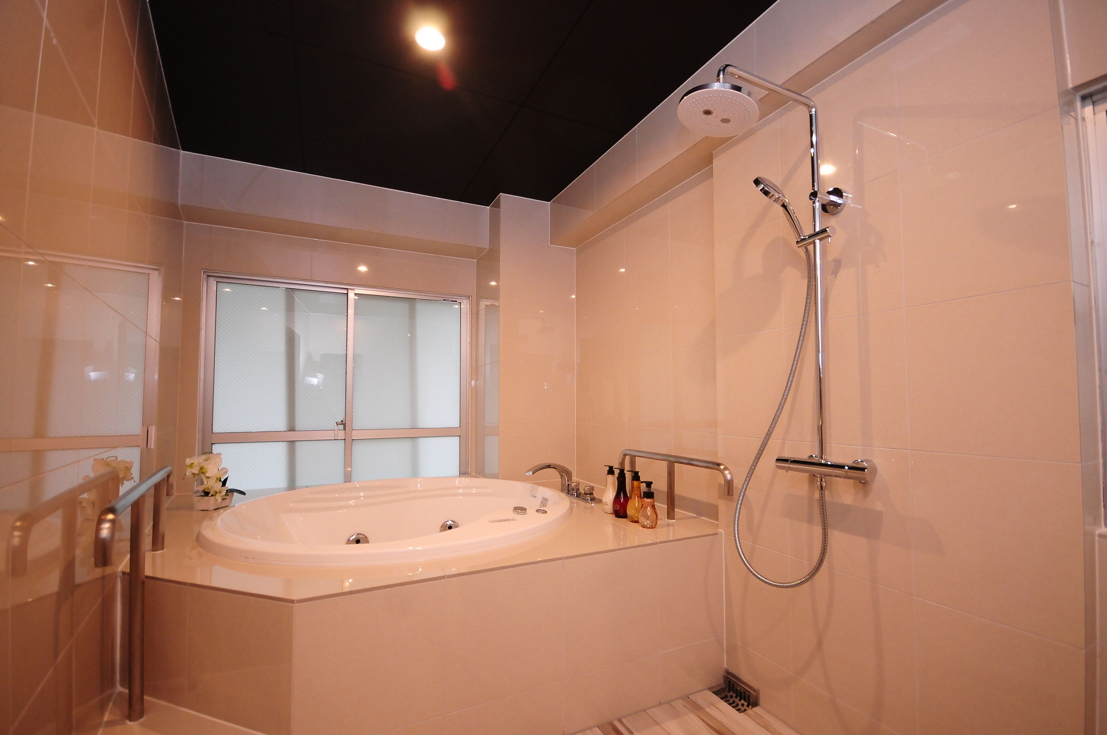 A modern bathroom with a large bathtub, a shower, and a window.