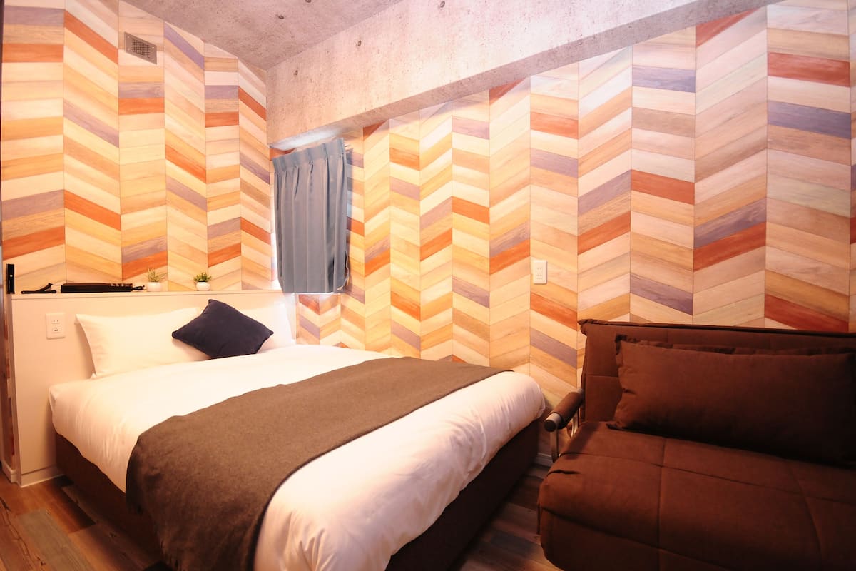 Una habitación con cama, sofá y ventana con cortinas.