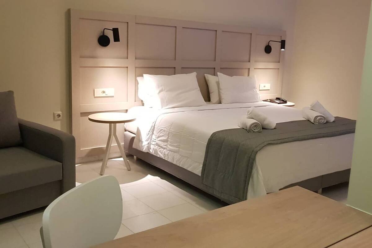 A hotel room with a bed, a small round table, a chair, and a sofa.