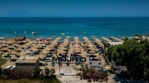 A beach resort with numerous sun umbrellas and lounge chairs, a clear view of the sea, and a distant mountain range. - Strofades Beach Hotel - All inclusive (Zakynthos)