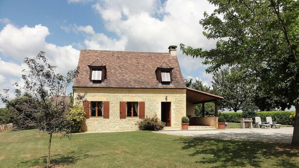 A two-story stone house with a sloped roof, a covered porch, and a well-maintained lawn. - Charming Perigord house in Salignac-Eyvigues, pets allowed (Salignac-Eyvigues)