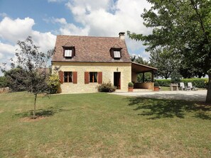 A two-story stone house with a sloped roof, a covered porch, and a well-maintained lawn. - Charming Perigord house in Salignac-Eyvigues, pets allowed (Salignac-Eyvigues)