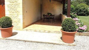 A covered patio area with a table and chairs, stone walls, and potted plants. - Charming Perigord house in Salignac-Eyvigues, pets allowed (Salignac-Eyvigues)