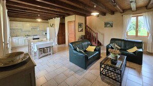 A spacious living area with a dining table, two leather sofas, and a kitchen in the background. - Charming Perigord house in Salignac-Eyvigues, pets allowed (Salignac-Eyvigues)