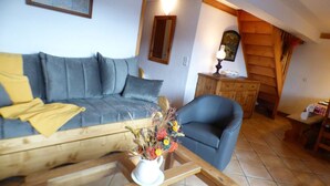 A cozy living room with a grey sofa, a blue armchair, and a wooden coffee table with a vase of flowers. - 4-Room Mezzanine Apt Les Saisies 10 guests (Villard-sur-Doron)