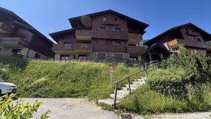 A multi-story building with balconies, a staircase, and a sign indicating a parking area. - 4-Room Mezzanine Apt Les Saisies 10 guests (Villard-sur-Doron)