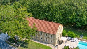 A stone building with a red-tiled roof, surrounded by lush greenery and a swimming pool. - Spacious house with private pool and pets allowed (Cénac-et-Saint-Julien)