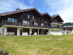 Un edificio a due piani con balconi e una zona salotto esterna coperta.