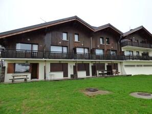 A multi-story building with balconies, large windows, and a grassy courtyard.