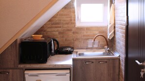 Una cocina compacta con microondas, lavamanos y refrigerador.