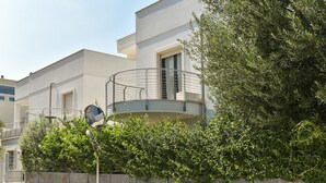 Een modern gebouw met balkon, metalen hekwerk en groen.