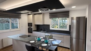 Una cocina moderna con una isla central, electrodomésticos de acero inoxidable y vistas al exterior.