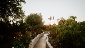 Un sendero de madera lleva a un mirador rodeado de exuberante follaje y plantas florecientes.