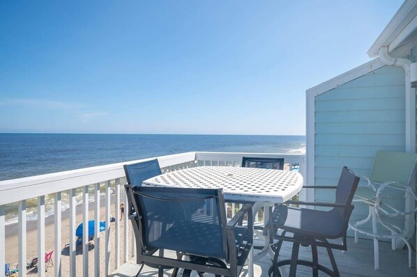 A balcony with a table and chairs overlooking the ocean. - Ocean Dunes 2005 Wait N Sea (Kure Beach)