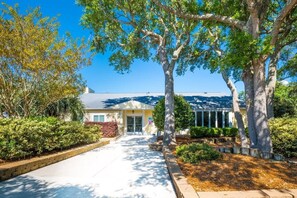 A residential house with a front yard, a driveway, and a large tree in the center. - Ocean Dunes 2005 Wait N Sea (Kure Beach)