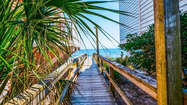 Ein Holzsteg führt zu einem Strand mit freiem Blick auf den Ozean.