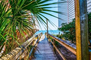 A wooden boardwalk leading to a beach with a clear view of the ocean.
