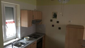 A kitchen with a window, sink, stove, and cabinets.