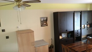 A compact kitchen with a wooden cabinet, a dining table, and a ceiling fan.