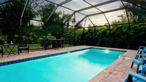 A covered swimming pool with a clear blue water surface, surrounded by a metal frame and glass panels.