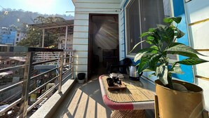 A balcony with a table, chairs, and a potted plant. - UbEx Home Rishikesh - Hostel (Narendranagar)