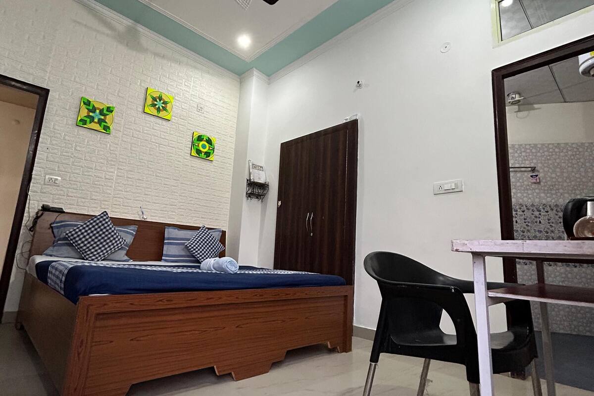 A bedroom with a bed, a desk, a chair, a wardrobe, and a ceiling fan.