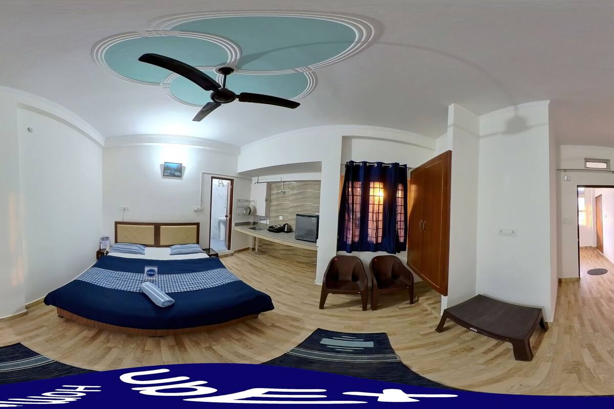 A room with a bed, a ceiling fan, a desk, and a chair.