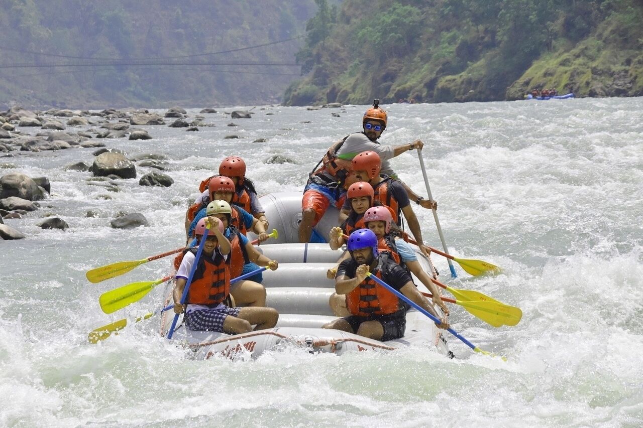 A group of people in an inflatable raft navigating a river with rapids.