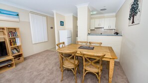 Cozy living space with a dining area, bookshelf, and kitchenette.