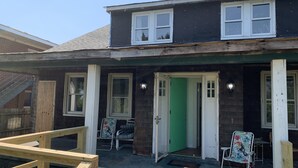 A two-story house with a green door, a covered porch, and a wooden deck. - Manor and Mutts #2 - Beach Front, Pet Friendly, Wi-Fi, Parking, W/D, King Bed (Norfolk)