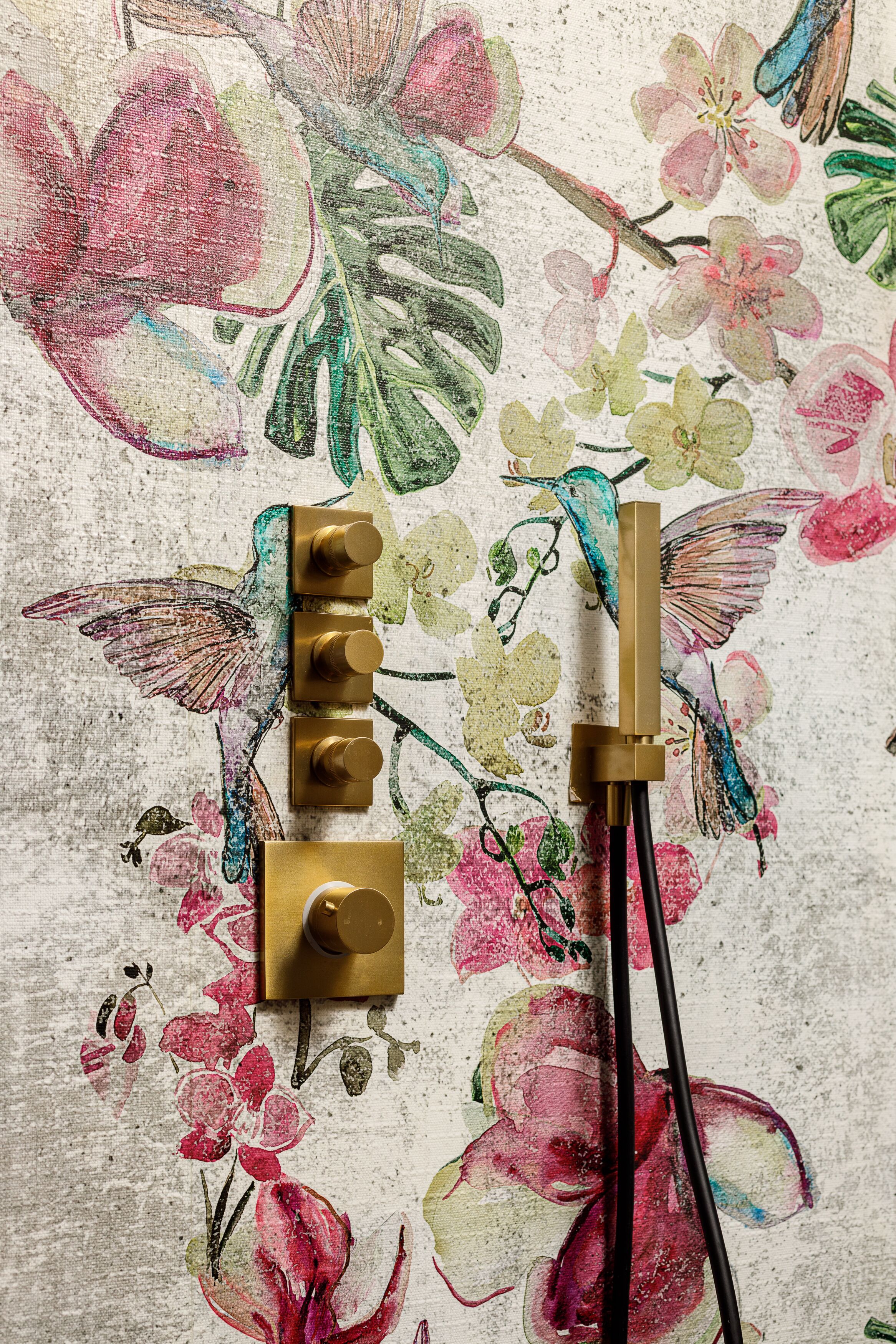 A wall with a floral pattern and a brass light switch.
