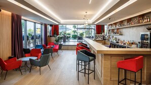 A modern bar area with a wooden counter, red and grey chairs, and a view of the outdoors. - Qosmo Brasov Hotel (Brasov)