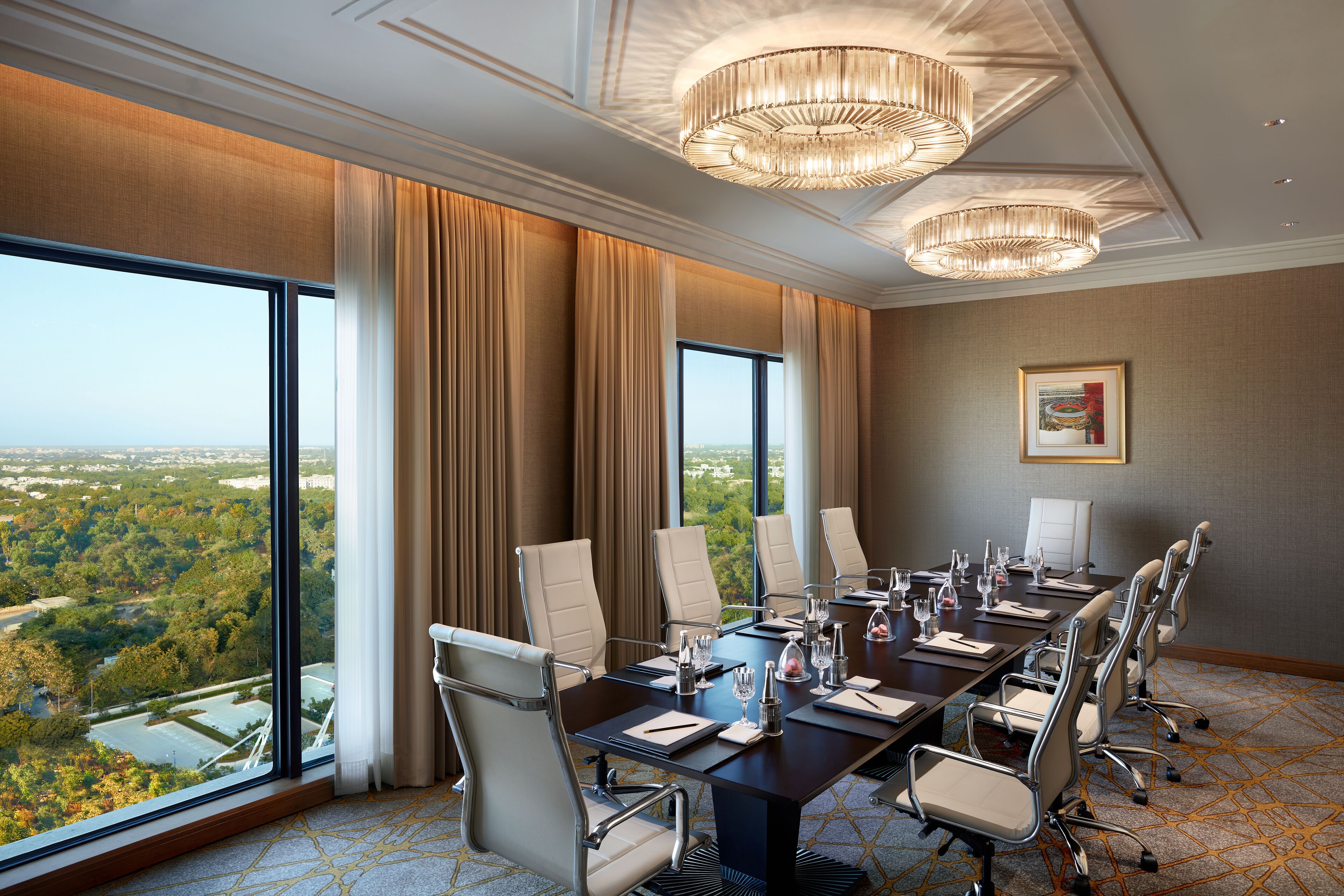 A conference room with a large table, chairs, and a view of a cityscape through large windows.