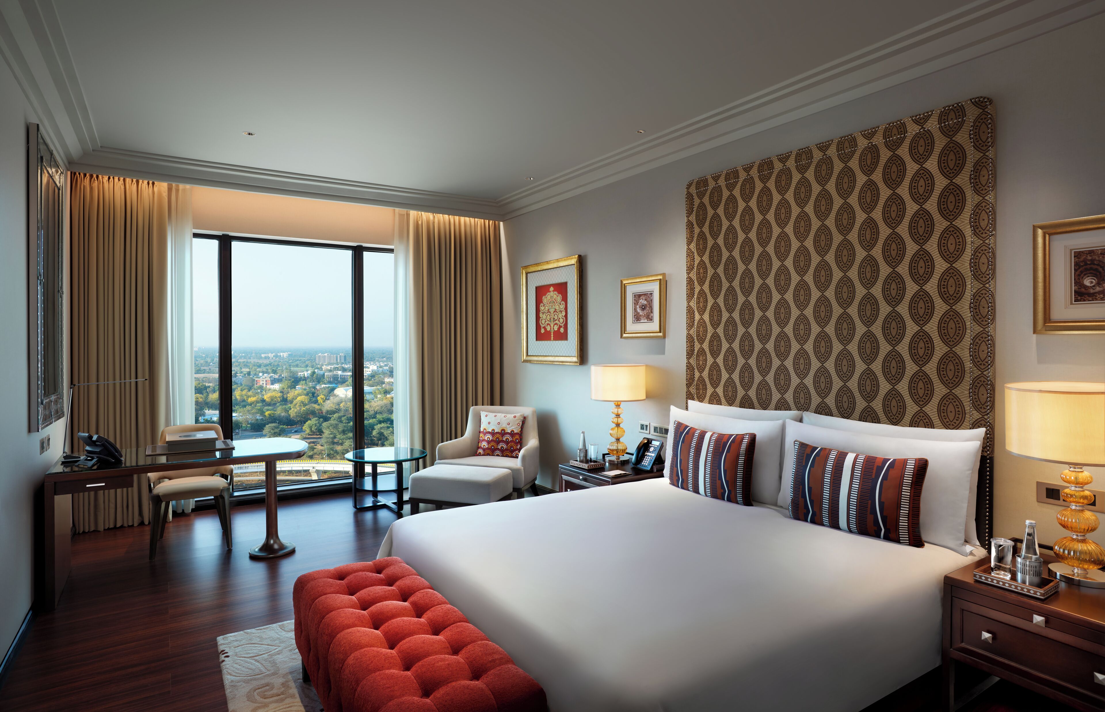 Habitación de hotel con una cama grande, un escritorio, una silla y vistas a la ciudad.