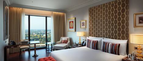 Habitación de hotel con una cama grande, un escritorio, una silla y vistas a la ciudad.