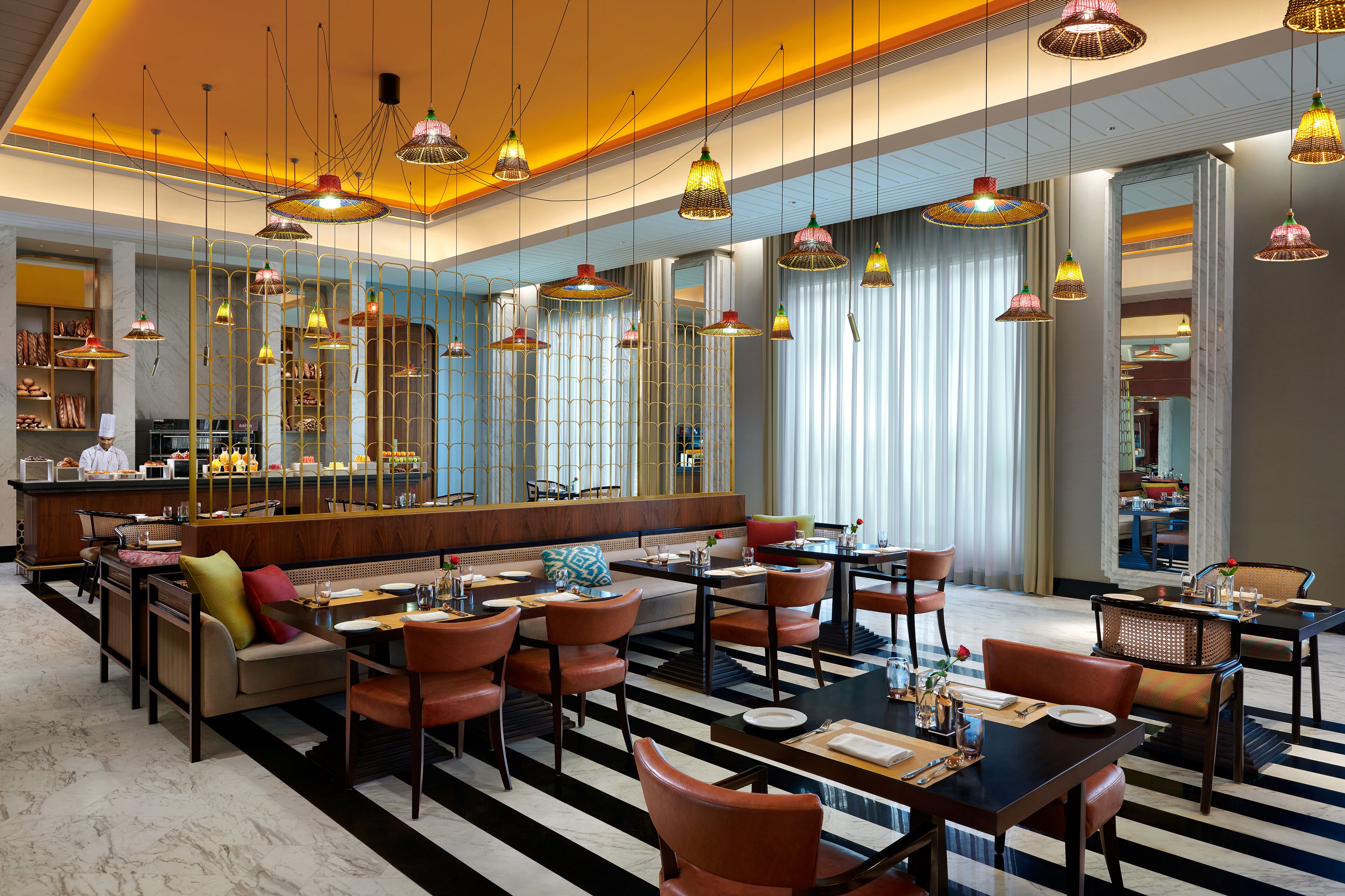 Een moderne hotellobby met een bar, zitgedeeltes en hangende pendantlampen.