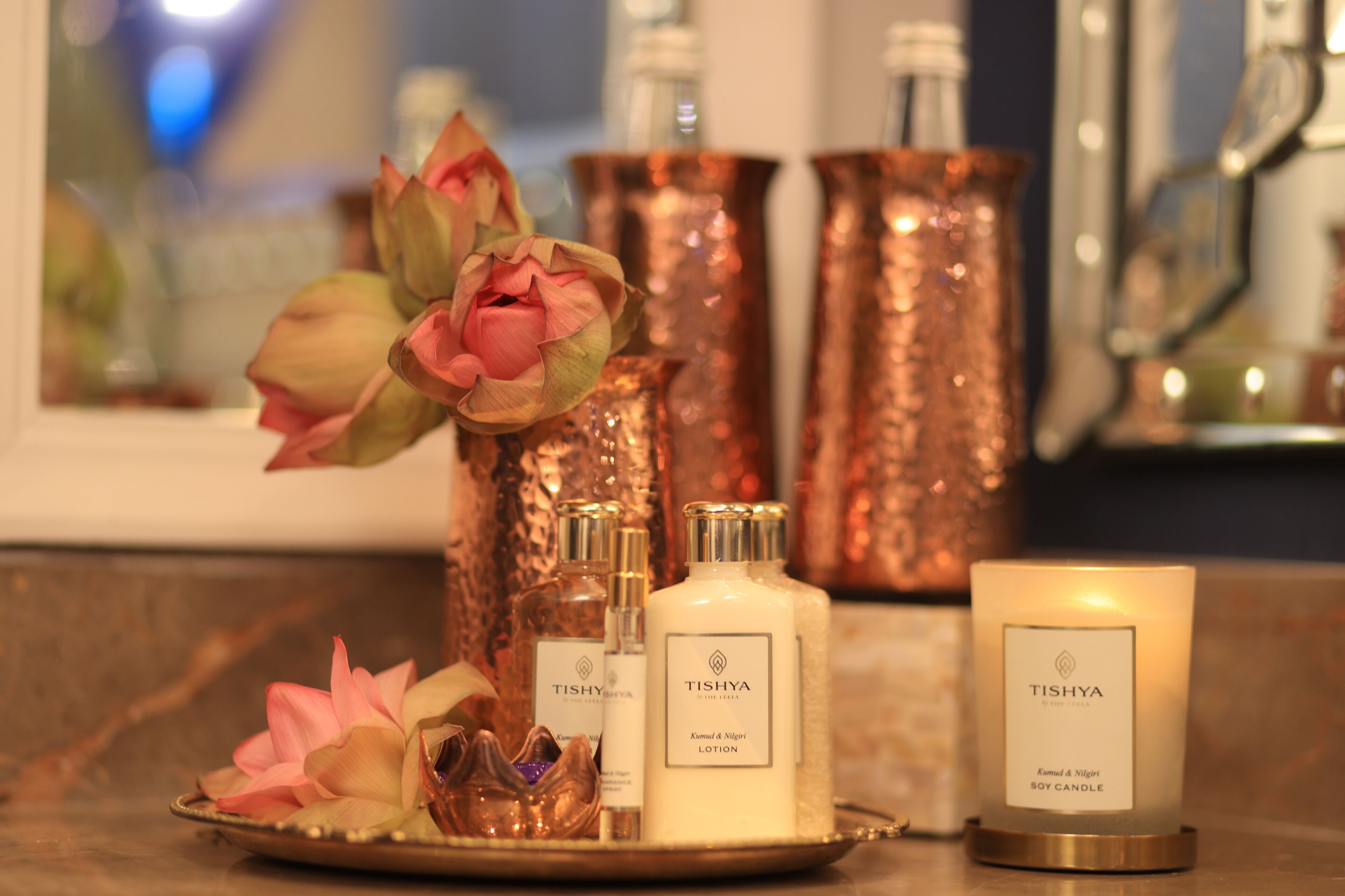 Una bandeja con varios productos de la marca Tishya, incluyendo una loción, una vela y adornos decorativos.