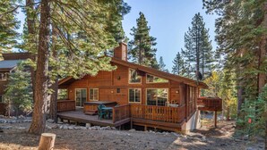 Une cabane en bois dotée d’une terrasse, entourée d’arbres.