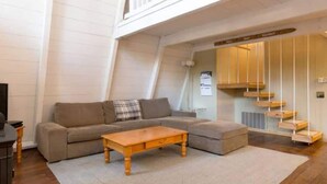 A modern living room with a sofa, coffee table, and a unique wooden staircase. - Zephyr by AvantStay | Stylish Frame w/ Access To Tahoe Donner (Truckee)