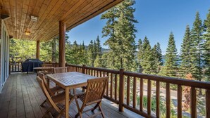 Eine Holzterrasse mit Tisch und Stühlen mit Blick auf ein bewaldetes Gebiet.