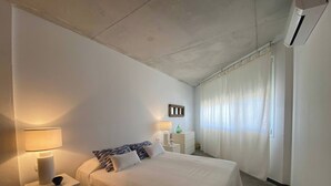 A bedroom with a bed, bedside tables, a lamp, a mirror, and a window with curtains. - Wonderful modern, spacious and comfortable villa (Fornells)