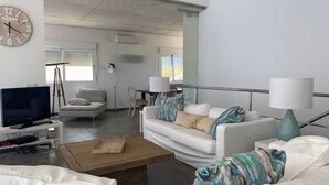 A modern living room with a television, white sofas, a coffee table, and a clock on the wall. - Wonderful modern, spacious and comfortable villa (Fornells)