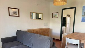 Una sala de estar con sofá gris, aparador de madera, mesa de comedor con sillas y un espejo en la pared.