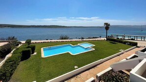 A swimming pool with a view of the sea, surrounded by well-maintained grass and a stone pathway. - Apartment in Fornells (Fornells)
