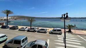 Une route côtière bordée de voitures garées, un passage piéton et une vue dégagée sur la mer.