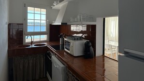 Une cuisine avec vue sur la mer, un lave-vaisselle, une cuisinière et un évier.