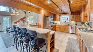 Una cocina moderna con armarios de madera, un refrigerador de acero inoxidable y una isla grande con taburetes de bar.